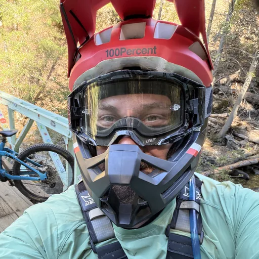 Ryan, the person who makes Quiver, in a full-face helmet on a bridge next to his trail bike
